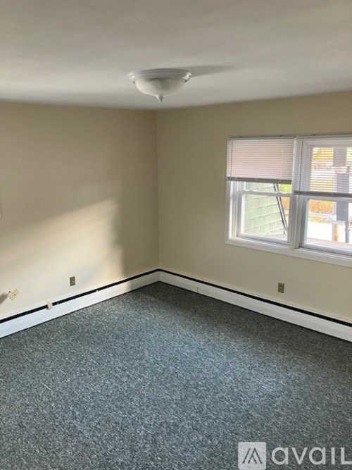A room with a carpeted floor and a window with blinds.