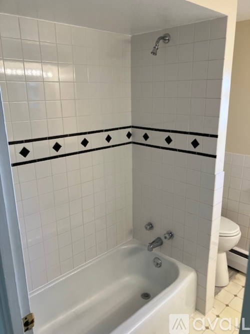 A white tiled bathroom with a black and white border.