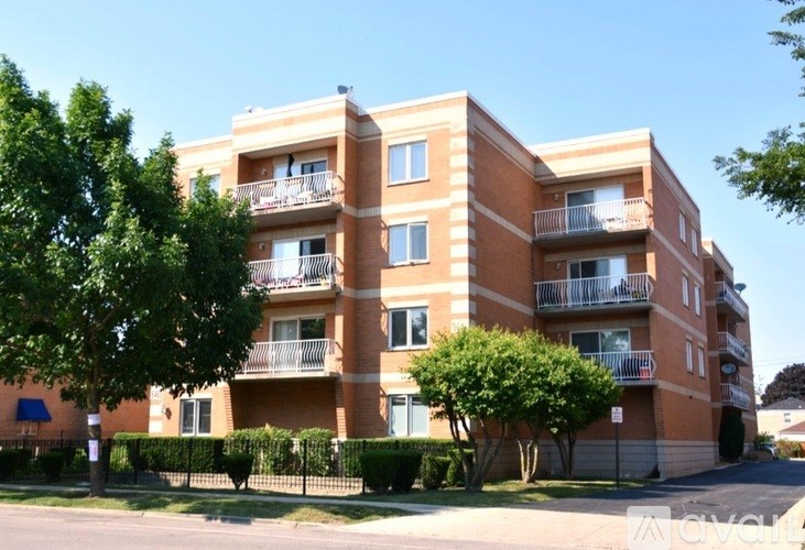 A large apartment building with balconies and trees in front.