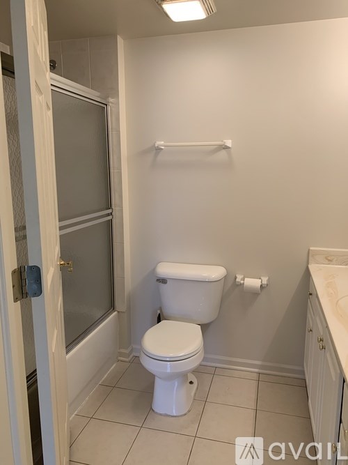 A white toilet in a small bathroom with a white cabinet and a white towel rack.