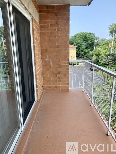 A balcony with a brick wall and a metal railing.