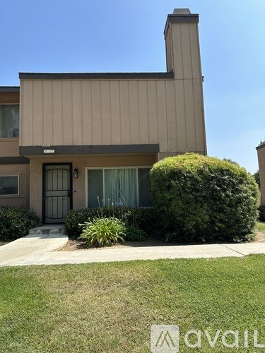 A house with a brown facade and a green bush in front.