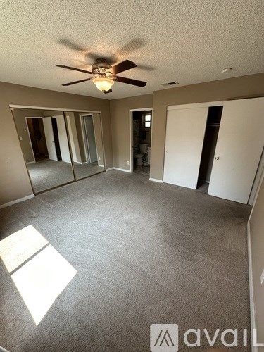 A spacious room with a ceiling fan and carpeted floor.