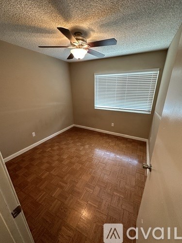 A room with a ceiling fan and a window with blinds.