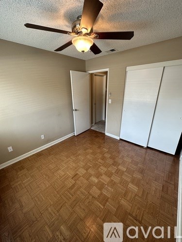 A room with a ceiling fan and wooden flooring.