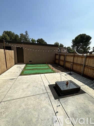 A backyard with a hot tub and a green mat.