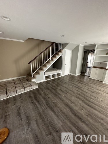 A living room with a staircase and a wooden floor.