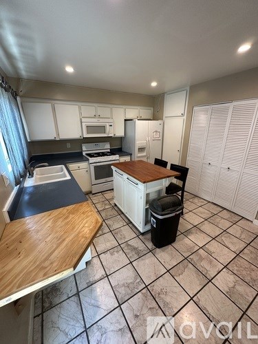 A kitchen with a wooden island in the middle.