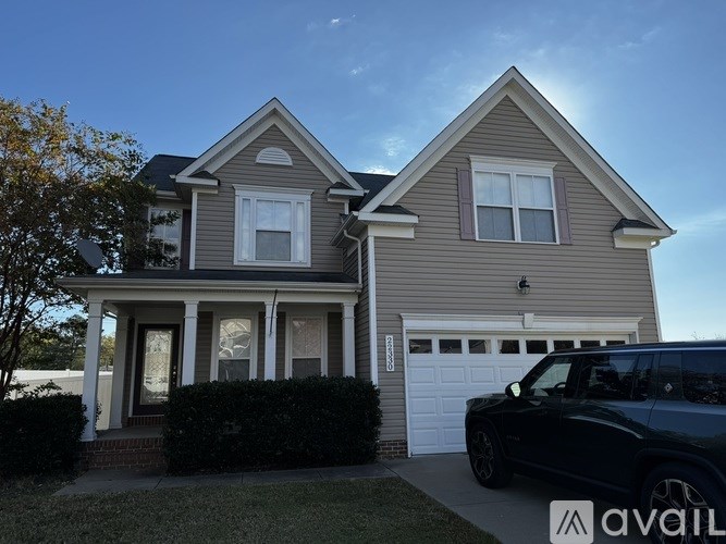 A two-story house with a garage and a car parked in front.