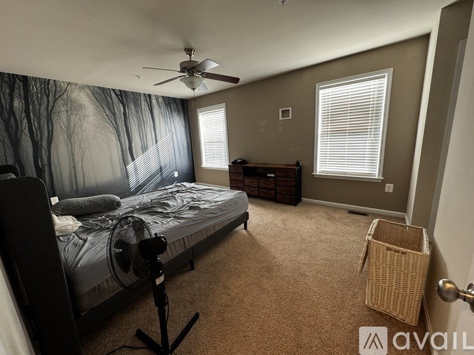 A bedroom with a bed, a ceiling fan, and a wall mural.