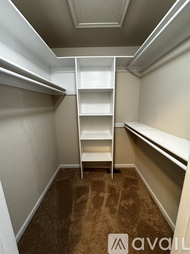 A carpeted walk-in closet with shelving and a bench.