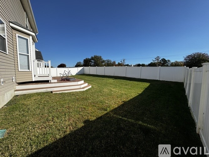 A backyard with a white fence and a house.