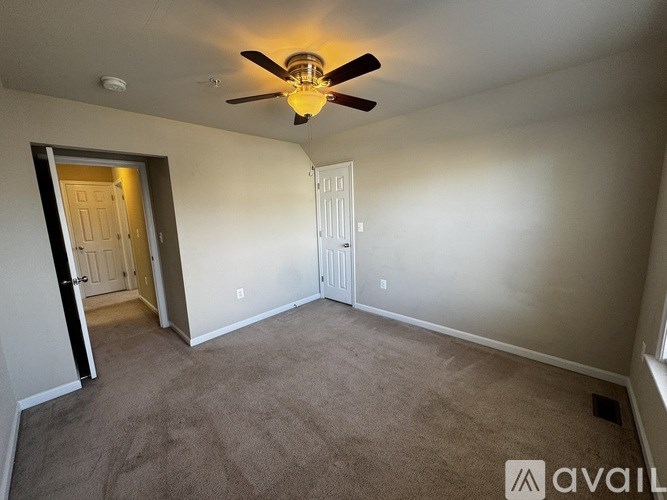 A room with a ceiling fan and carpeted floor.