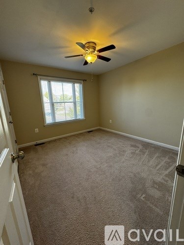 A room with a carpeted floor, a ceiling fan, and a window with blinds.