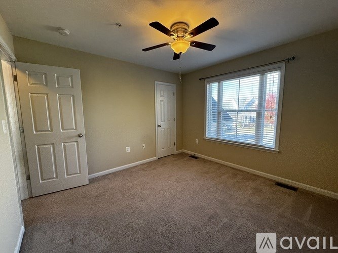 A room with a ceiling fan and carpeted floor.