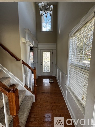 A hallway with wooden floors and a chandelier.