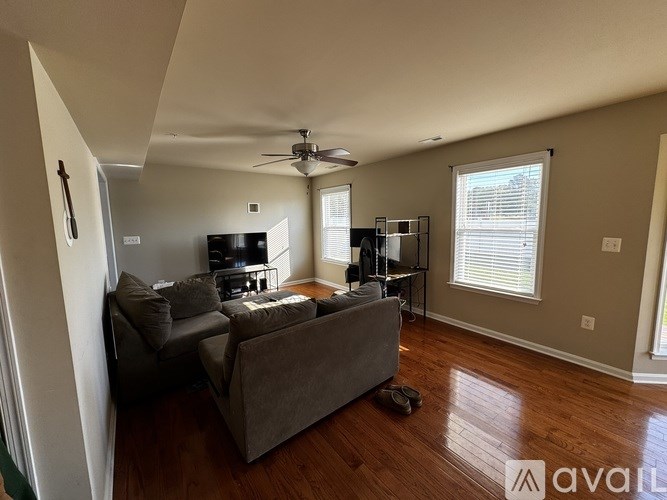 A living room with a couch, television, and a fan.