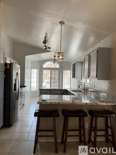 A kitchen with a marble countertop and bar stools.
