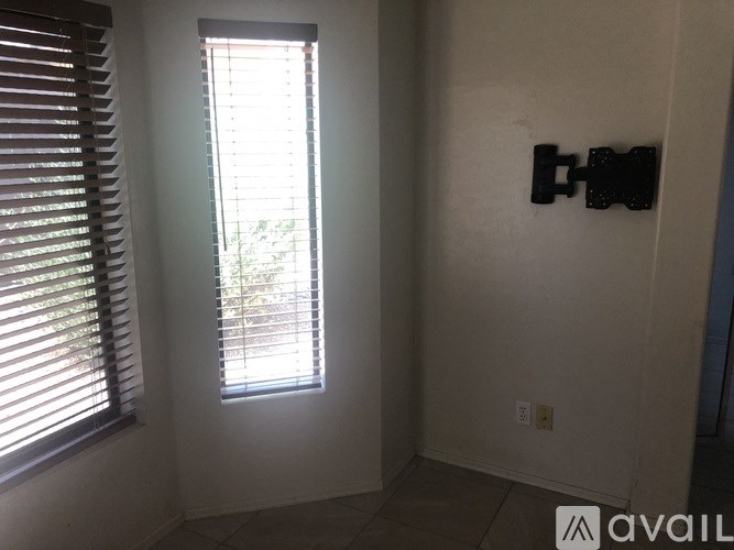 A room with a window covered by blinds and a wall-mounted TV.