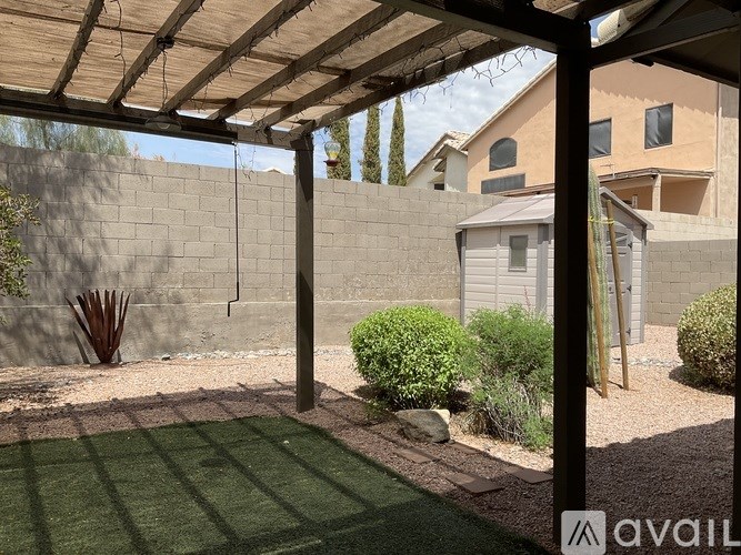 A patio area with a wooden pergola and a green lawn.