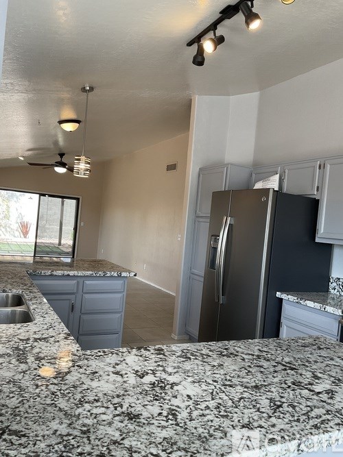 A kitchen with granite countertops and a stainless steel refrigerator.