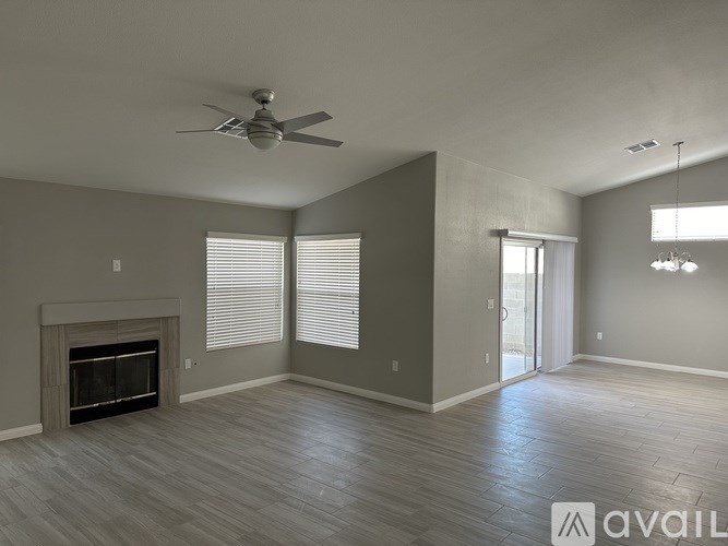 A spacious living room with a fireplace and a ceiling fan.