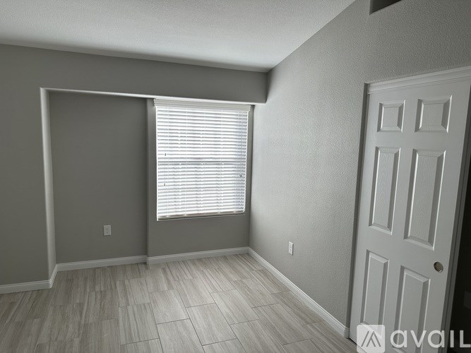 A room with a door, a window with blinds, and a wall with a switch.