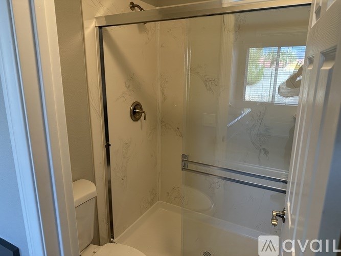 A bathroom with a glass shower door and a toilet.