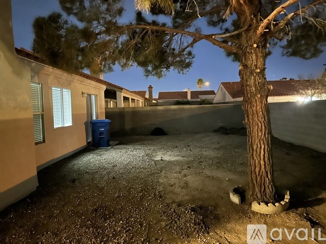 A tree stands in a courtyard between two buildings at night.