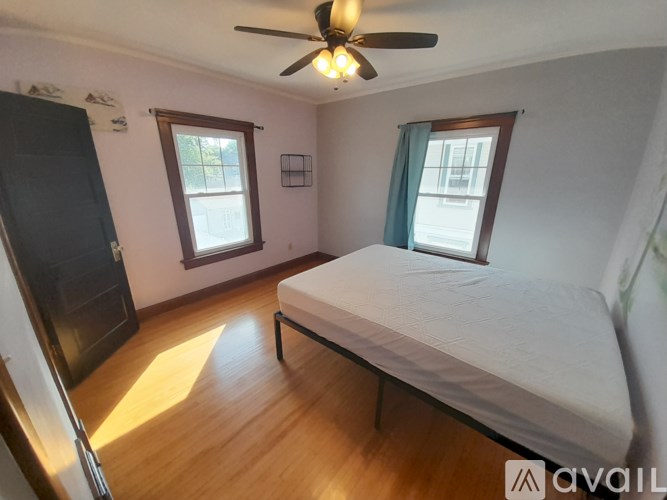 A bedroom with a bed, a ceiling fan, and two windows.