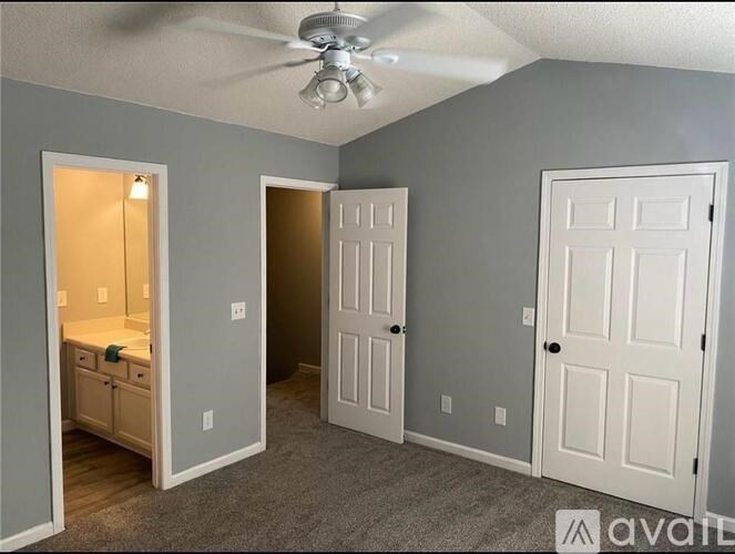 A room with a ceiling fan and three doors.