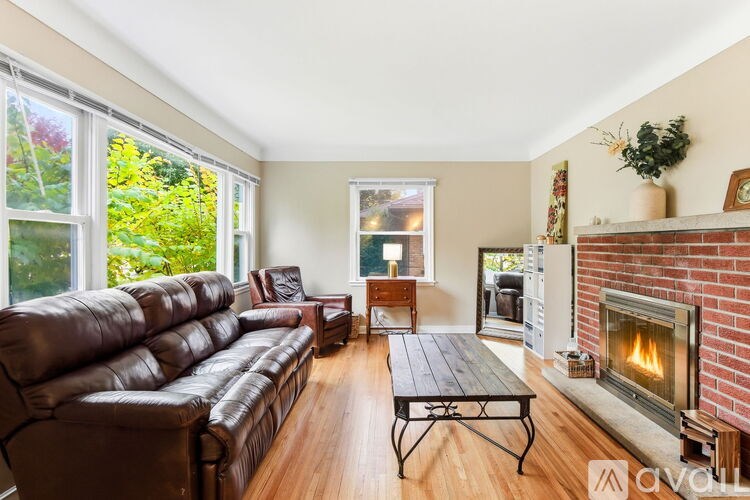 A living room with a brown leather couch, a fireplace, and a dining table.