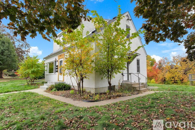 A house with a yellow front door and a tree in front of it.