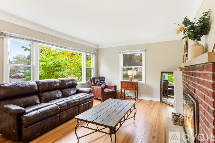 A living room with a brown leather couch, a wooden coffee table, and a fireplace.