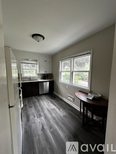 A kitchen with a white fridge and a table with a red cushion.