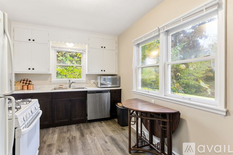 A kitchen with white appliances and wooden floors.