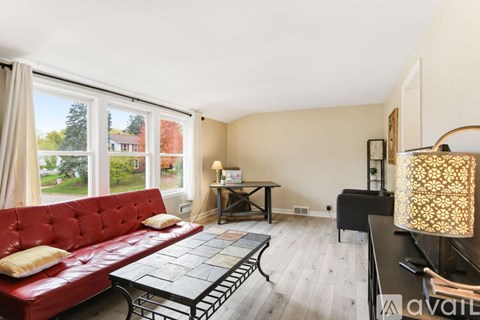 A living room with a red couch and a glass table.