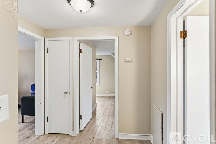 A hallway with a white door and a black sofa.