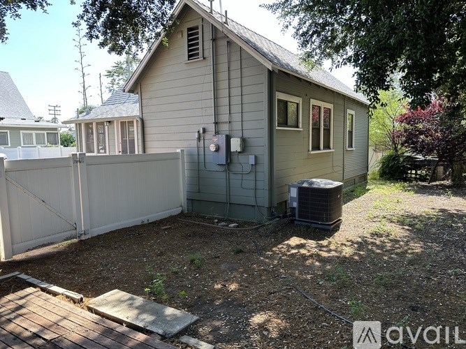 A house with a fence and a tree in front of it.