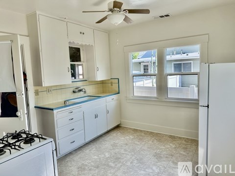 A kitchen with white cabinets and a tiled floor.