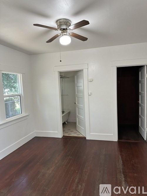 A room with a ceiling fan and wooden floors.