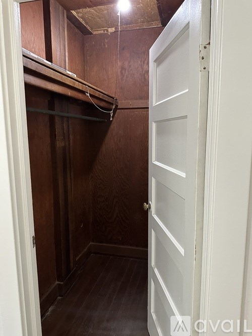 A small, dark wooden closet with a white door.