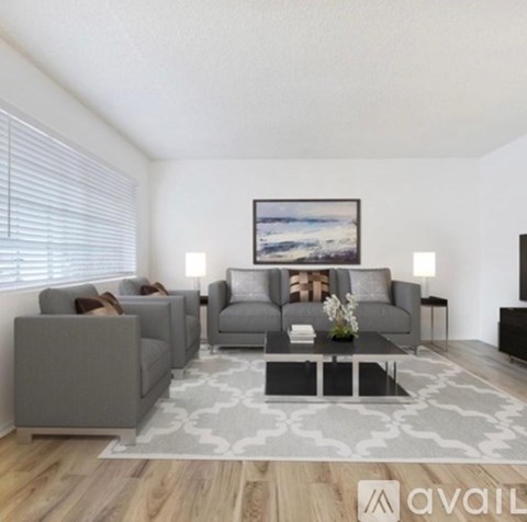 A living room with a grey couch, a coffee table, and a painting on the wall.