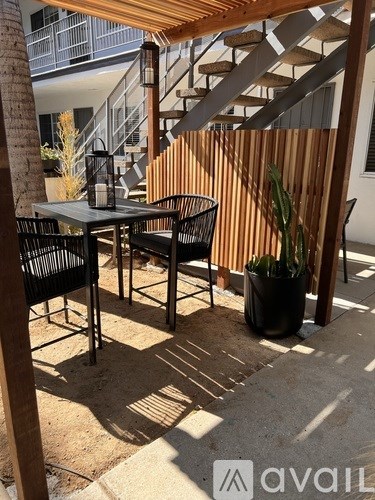 A patio with a table and chairs under a wooden roof.