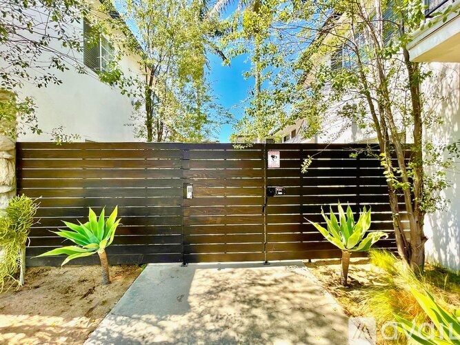 A brown fence with a gate and a small garden in front.