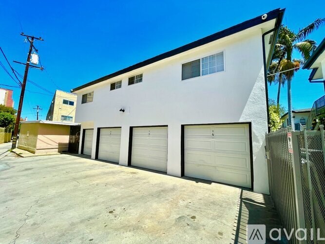 A white building with a black roof and four garage doors.