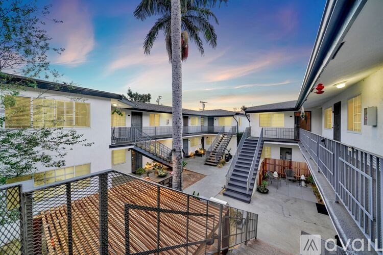 A sunset view of a residential area with a palm tree and apartment buildings.