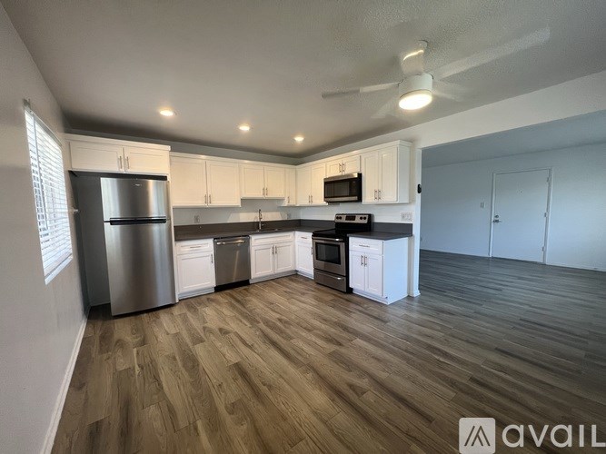 A modern kitchen with wooden flooring and stainless steel appliances.