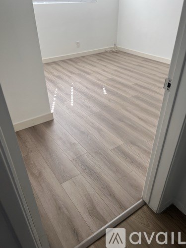 A room with wooden flooring and a door on the right.