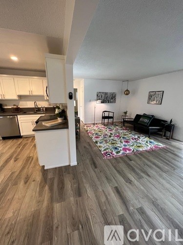 A kitchen with white cabinets and a wooden floor.